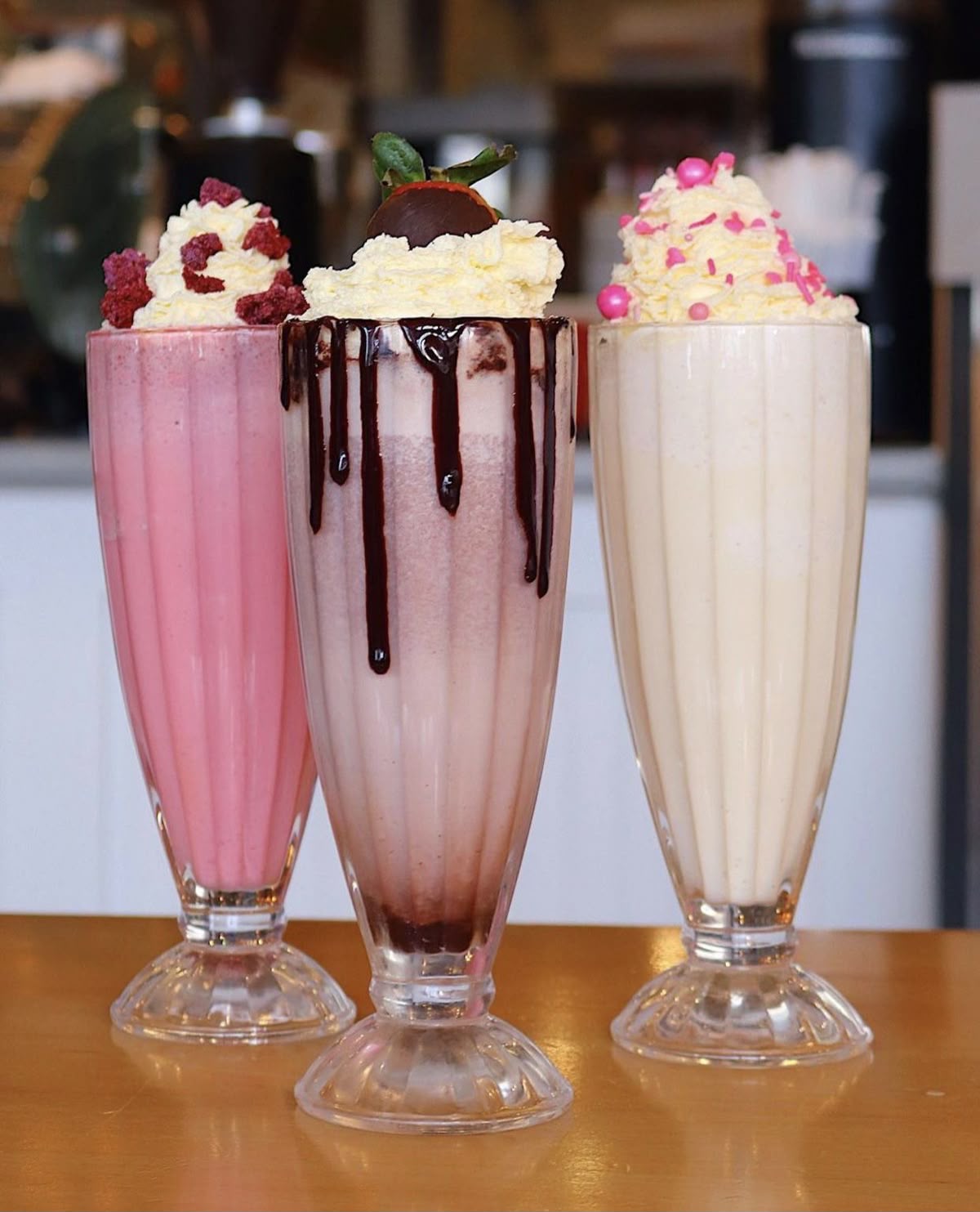 Three classic milkshakes — strawberry, chocolate and vanilla — topped with cream