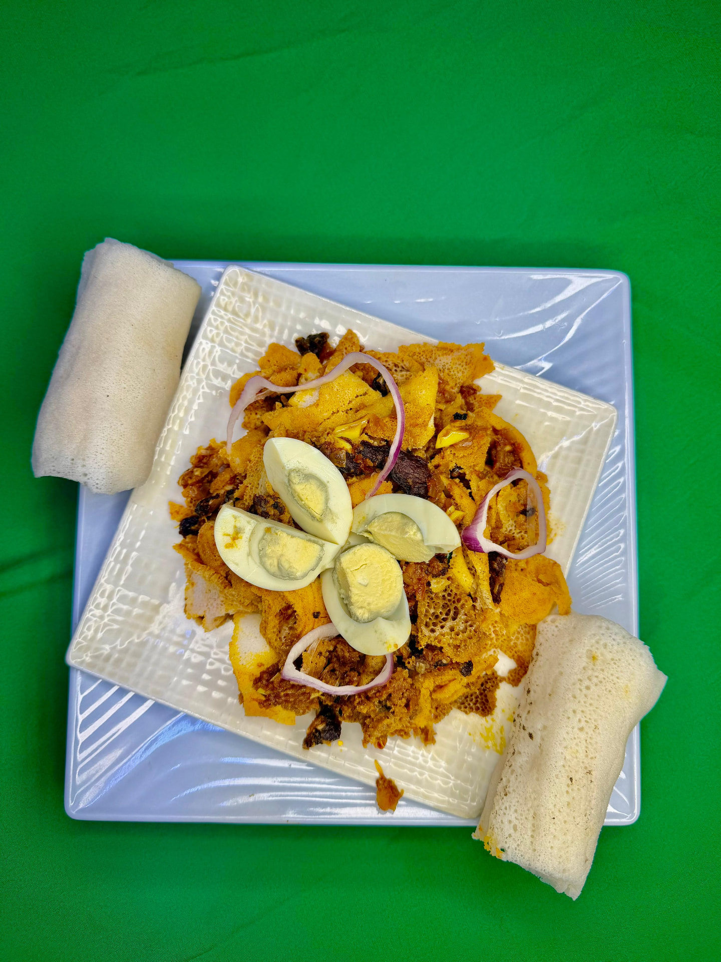 Ethiopian firfir served with boiled egg, red onion and rolls of injera