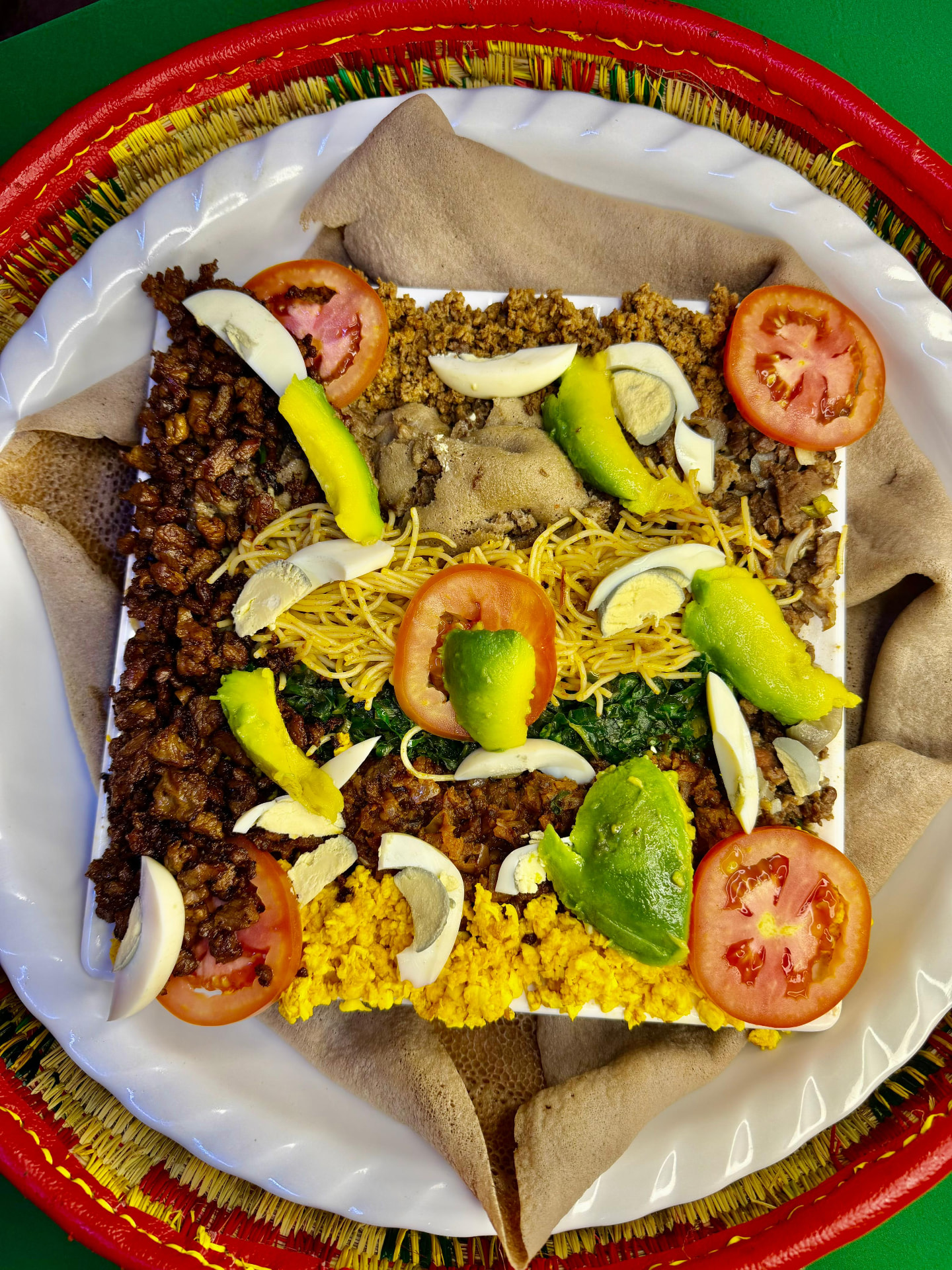 Murtesa Special VIP platter with steamed and fried kitfo, goma vegetables and boiled eggs on brown teff injera