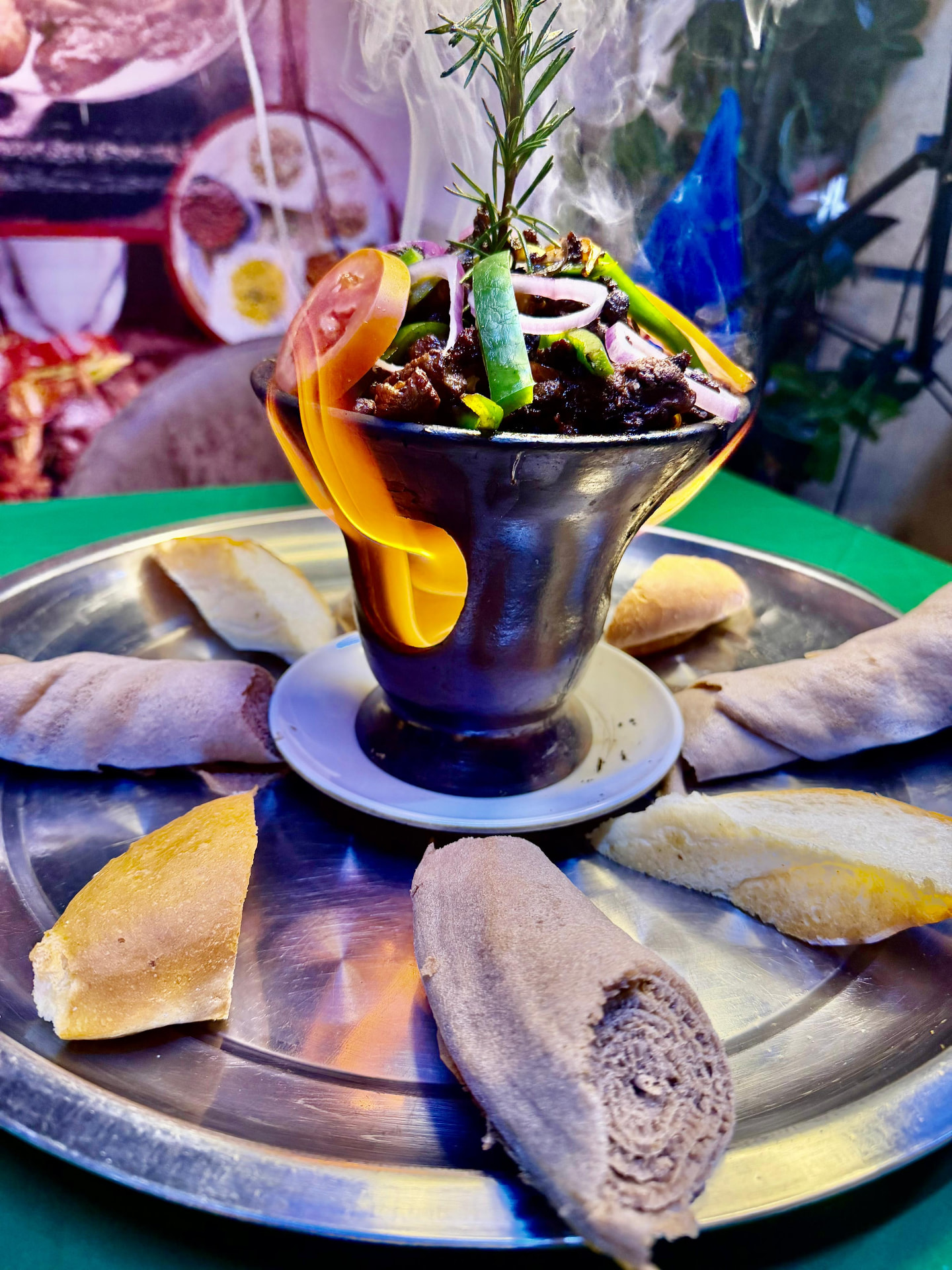 Ethiopian shekle tibs, sliced beef sizzling in a traditional clay dish over hot coals