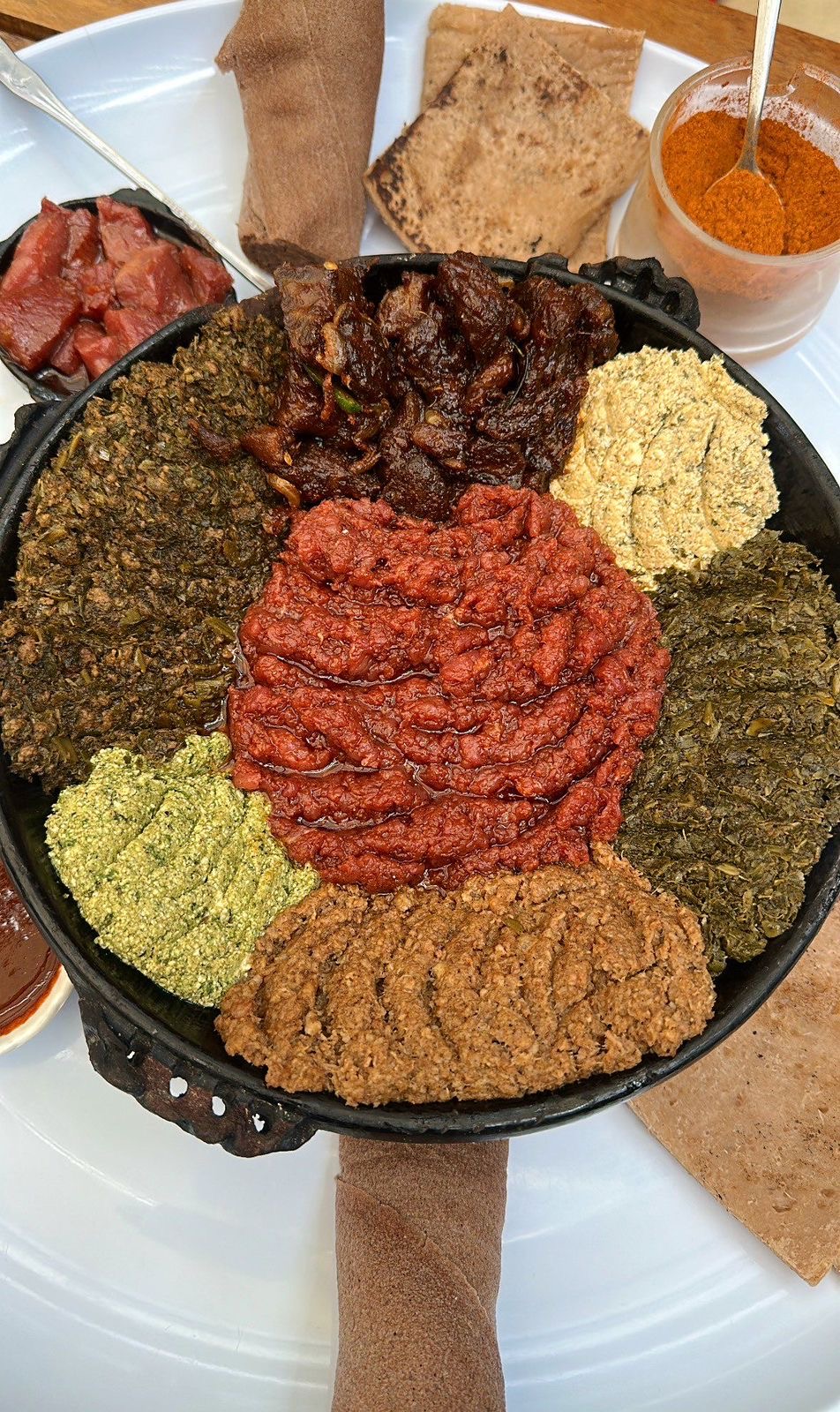 Ethiopian beyaynetu combination platter with collard greens, lentil and pea purees, tibs and kitfo