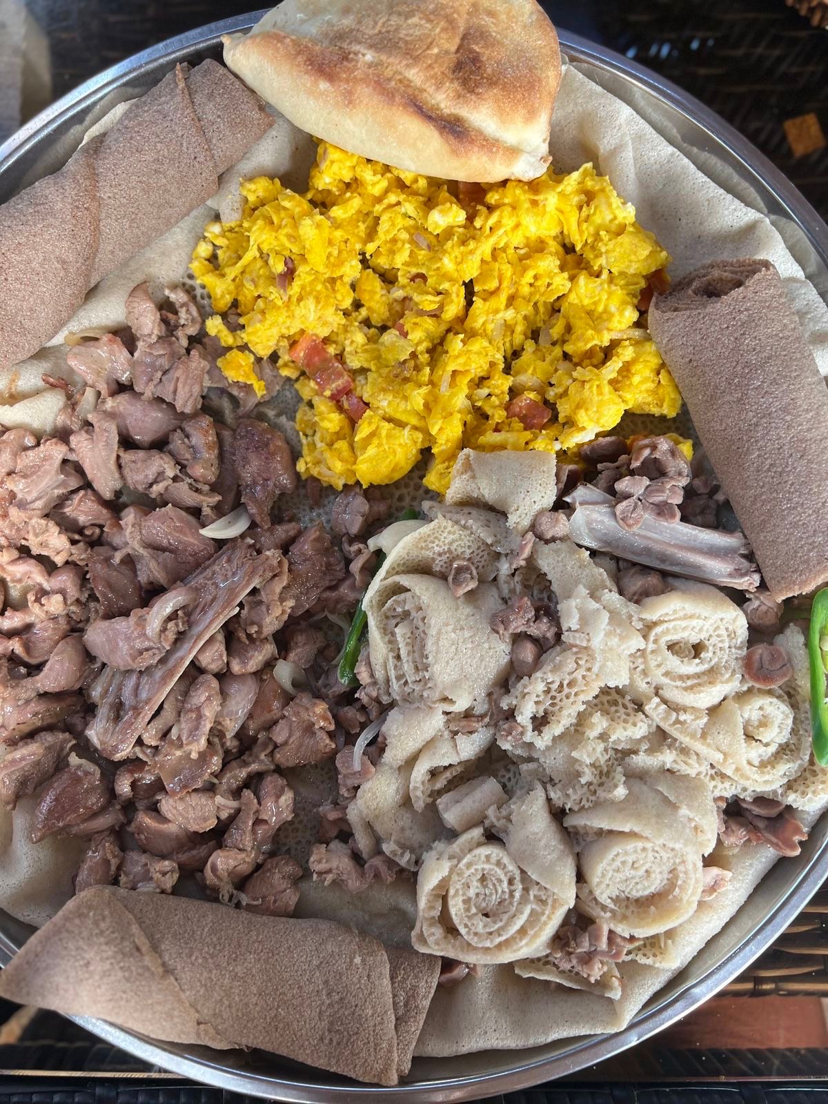Ethiopian breakfast combination platter with tibs, scrambled eggs, kikil and injera