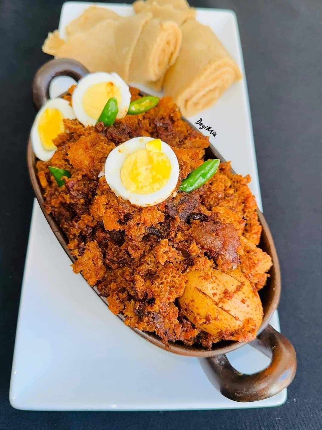 Ethiopian fitfit topped with boiled eggs and green chilli, served with rolled injera
